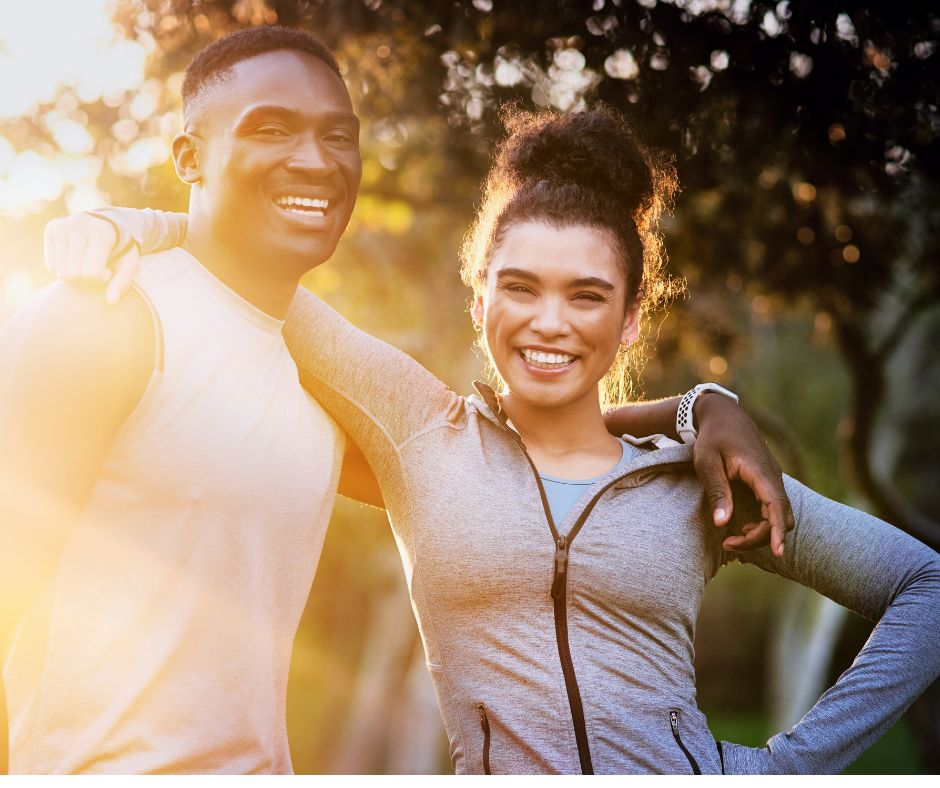 A smiling man and woman stand together in workout clothes